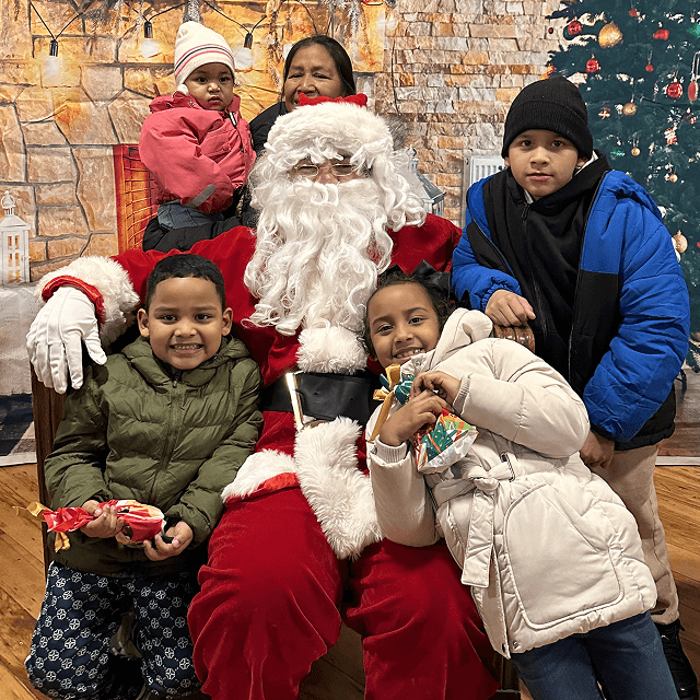 Santa Claus posing with children and a parent during VIA’s Annual Toy Drive and Christmas celebration.