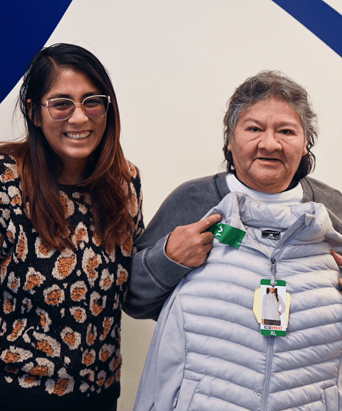 Volunteer and recipient smiling while holding a new winter coat during VIA’s Annual Winter Coat Drive.