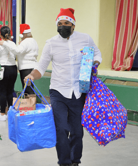 Volunteer carrying large gift bags and presents during VIA’s Toy Drive event.